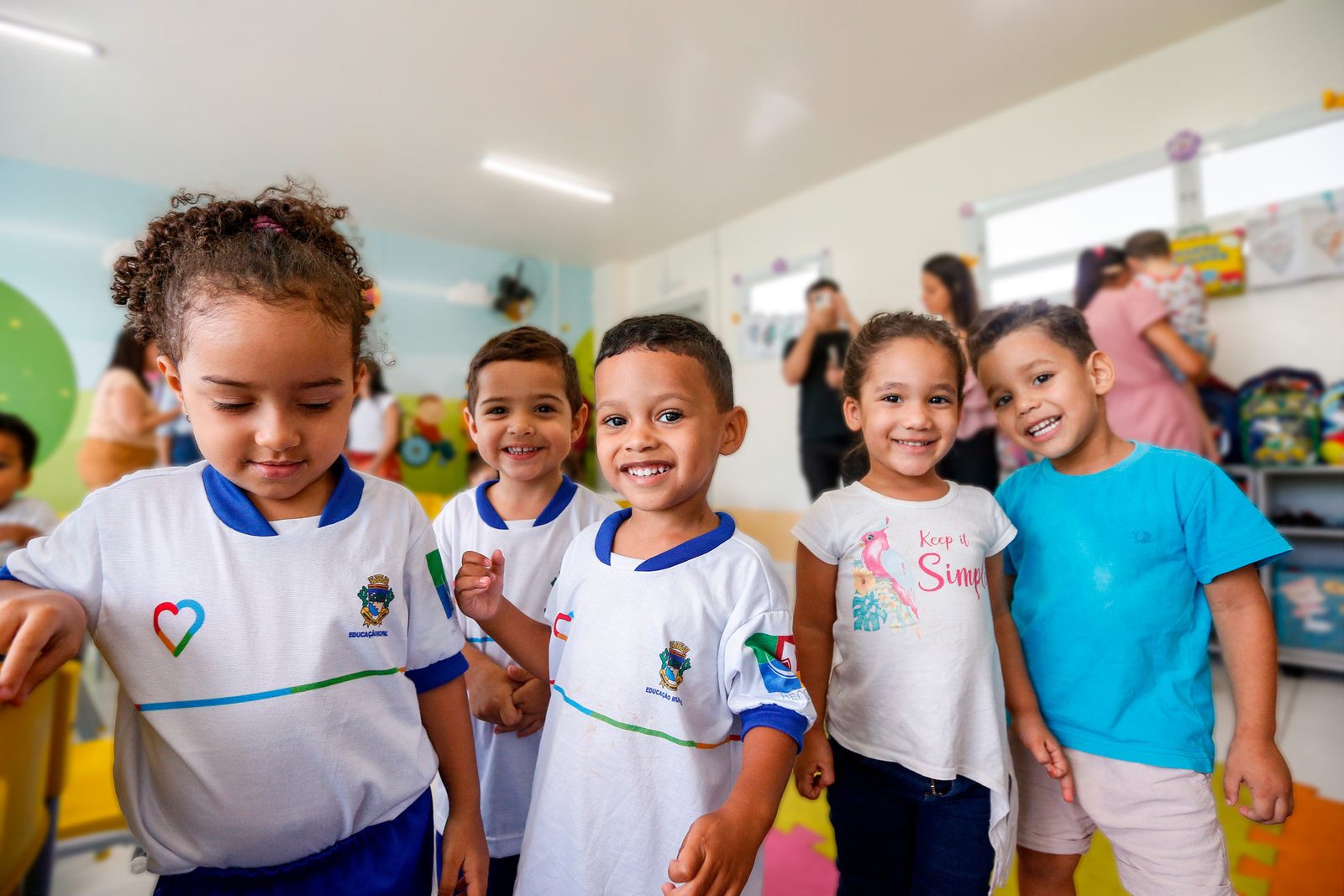 Crianças de uniforme sorrindo em uma sala de creche